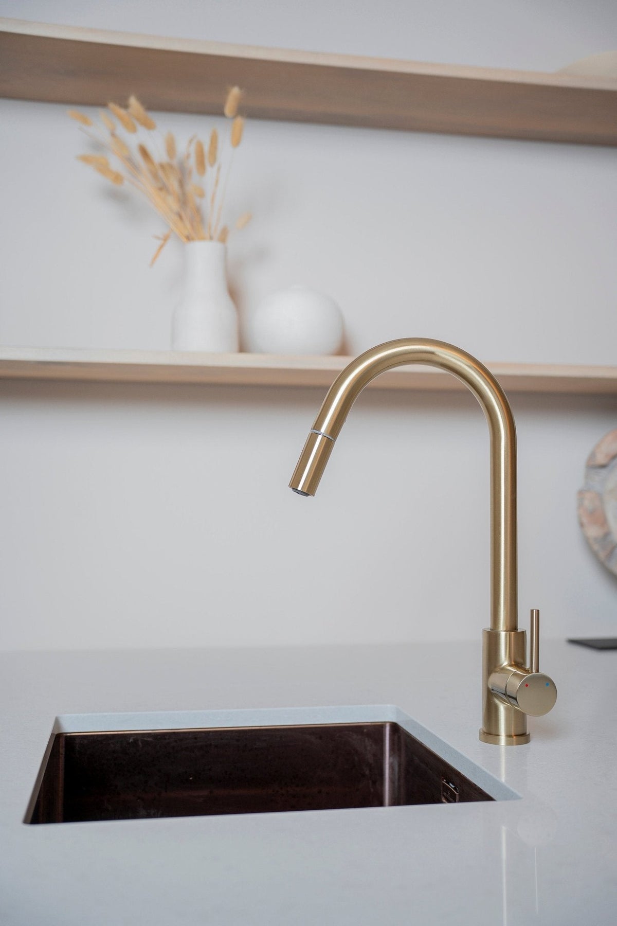 Uittrekbare keukenkraan Silana in goud bij een spoelbak